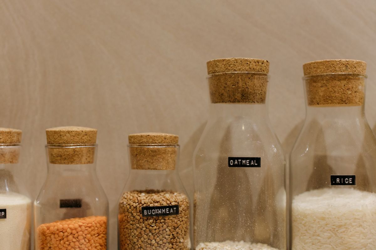 Cork-stoppered glass jars of grains and flour with small chalk labels