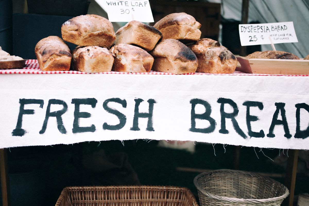 Loaves of fresh bread on display at a market stall with hand-painted signs