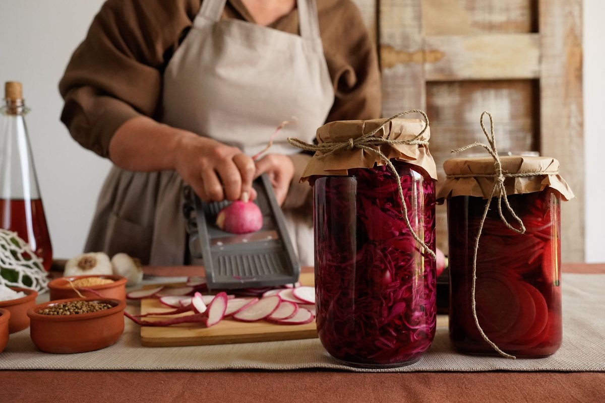 Woman preparing fermented vegetables with jars on the counter